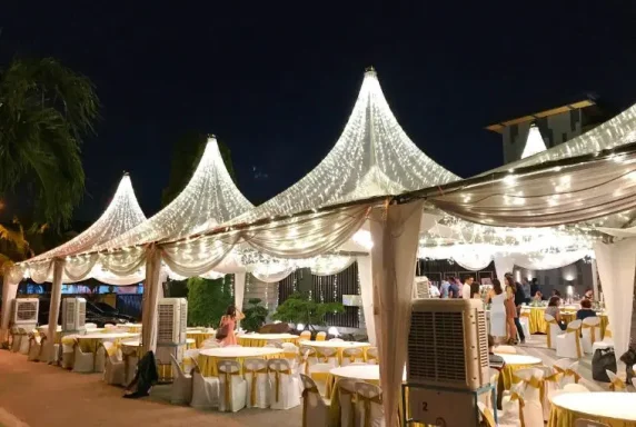 Elegant outdoor dining venue with illuminated tents and decorated tables at night.